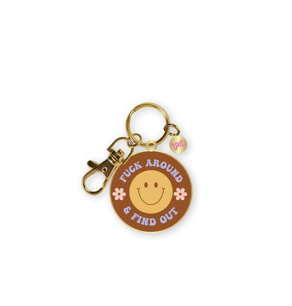 Round brown enamel keychain with gold edging and hardware says, "Fuck Around & Find Out" in blue retro-styling lettering with pink floral accents around a central yellow smiley face