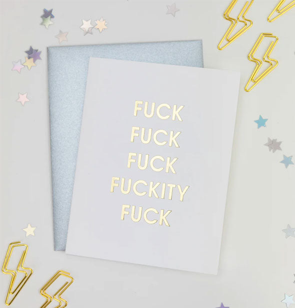 Fuck Fuck Fuck Fuckity Fuck greeting card and silver envelope are staged with gold lightning bolt paper clips and star confetti