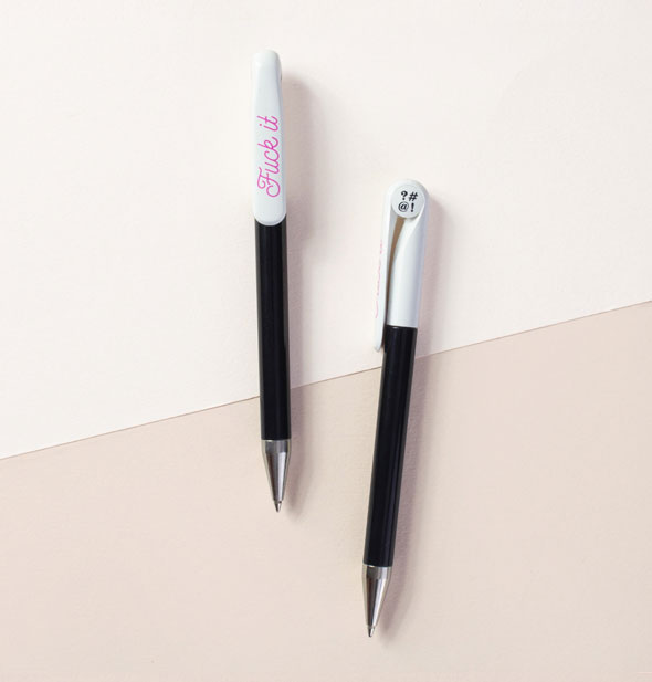 Black and white pens feature grawlix symbols in black at the top and the words, "Fuck it" in pink script along the clip