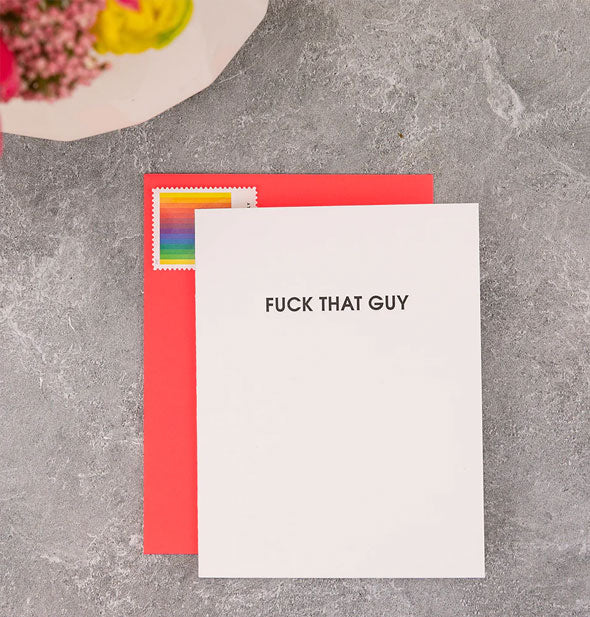 Fuck That Guy greeting card rests on a gray marble countertop with red envelope affixed with a rainbow postage stamp