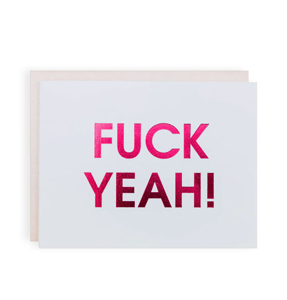 White greeting card with pastel pink envelope partially visible behind it says, "Fuck yeah!" in large metallic pink foil lettering