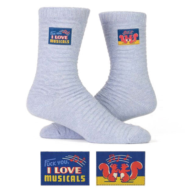 Light gray-blue socks with colorful sewn-on labels that say, "Fuck you, I love musicals" and feature two singing squirrels