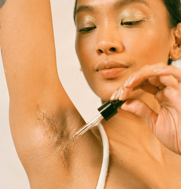 Model applies oil to armpit with dropper