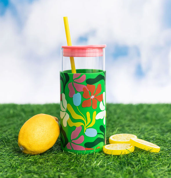 Green Geometric Floral Glass Tumbler on green astroturf against a blue sky with white cloud background flanked by a lemon and lemon slices