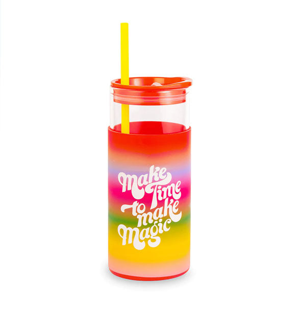 Clear class cylindrical drink tumbler with red lid, yellow straw, and rainbow ombre silicone sleeve that says, "Make Time to Make Magic" in white lettering