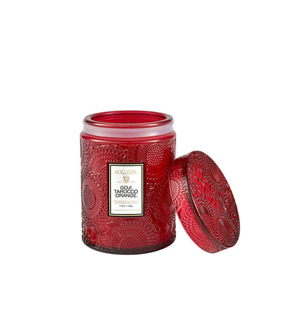 Petite red embossed glass jar candle with lid set to the side