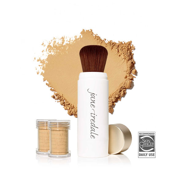 White Jane Iredale powder brush with gold cap removed and set to the side, two refill canisters nearby, and an enlarged product sample in the background in shade Golden Glow