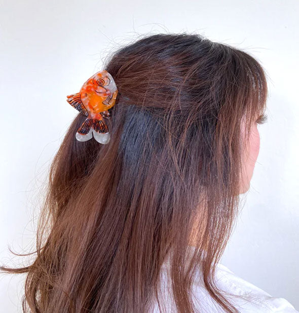 Model wears a goldfish hair clip in a partially swept-back style