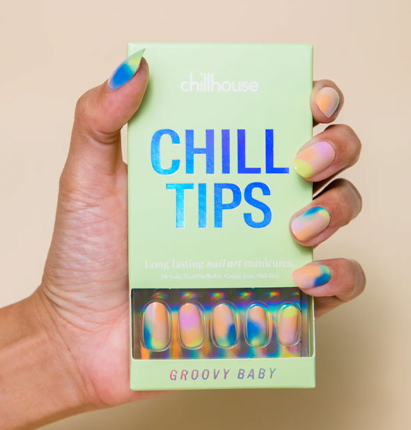 Model wears a set of of multicolor tie dye effect press-on nails and holds a Chillhouse Chill Tips box of the same style: Groovy Baby
