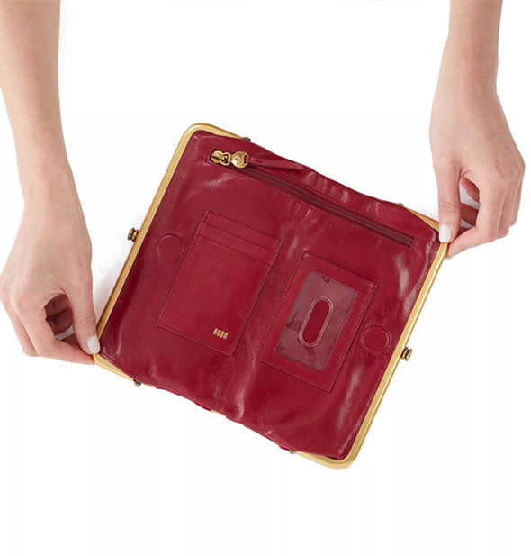 Model holds open a red leather wallet to reveal storage pockets inside