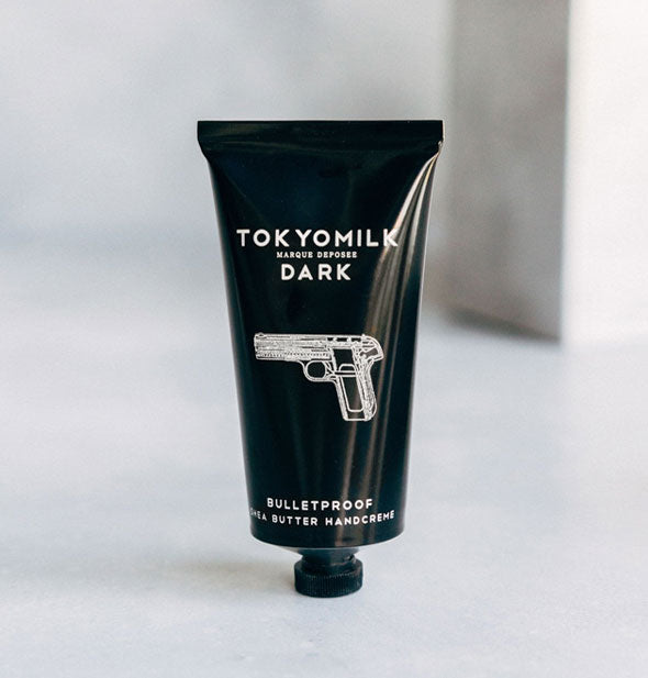 Black tube of TokyoMilk Bulletproof Shea Butter Handcreme with white lettering and handgun graphic