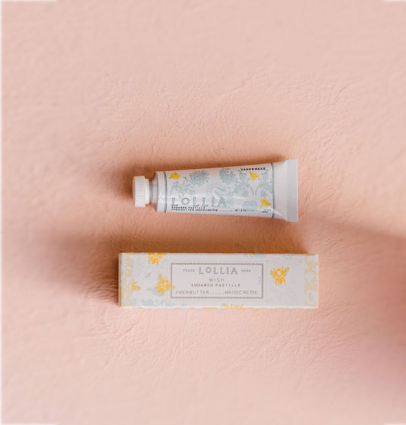 Mini white tube and box of Lollia Wish Handcreme both feature blue floral patterning with gold bee accents