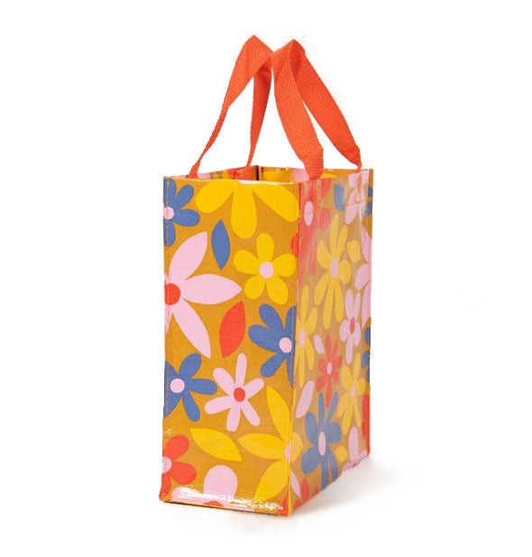 Brown tote bag with reddish-orange top handles features an all-over floral design in red, pink, yellow, and blue