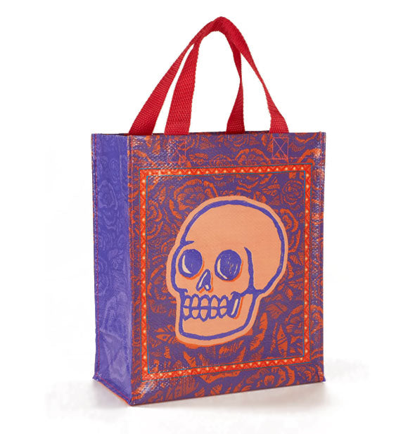 Red, purple, and pink tote bag with red handles features a rose pattern with skull illustration overtop