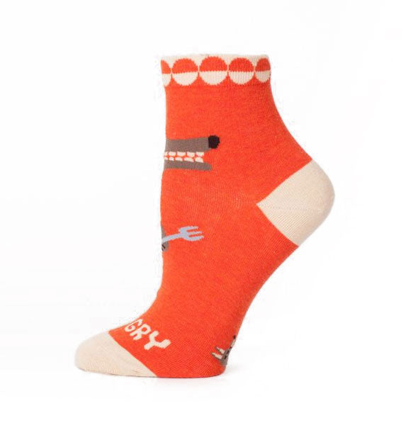 Orange socks with white details feature a monster holding a knife and fork above the word, "Hangry"