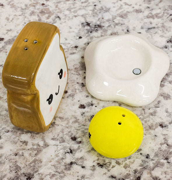 Toast and egg salt and pepper shakers shown from above to reveal their holes and also a magnetic feature in the white of the egg that holds the yolk in place