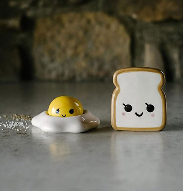 Happy toast and egg salt and pepper shakers on a marble surface sprinkled with spices