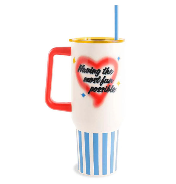 Large drink tumbler with blue and white striped base, white body, red handle, yellow lid, and blue straw features a heart and stars design with the words, "Having the most fun possible" in airbrush-style black script lettering