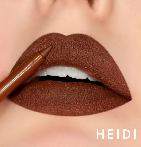 Model's lips wear shade Heidi of Kara Beauty Line Up Lip Liner; pencil tip is held up to upper lip