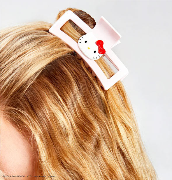 Model wears a Hello Kitty face claw clip in a part-up twisted hairdo