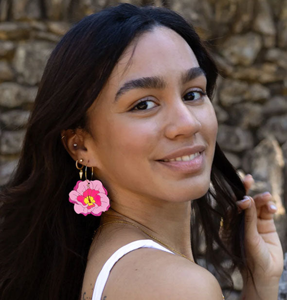 Smiling model wears pink hibiscus flower hoop earrings