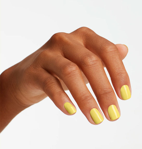 Model's hand wears yellow nail polish