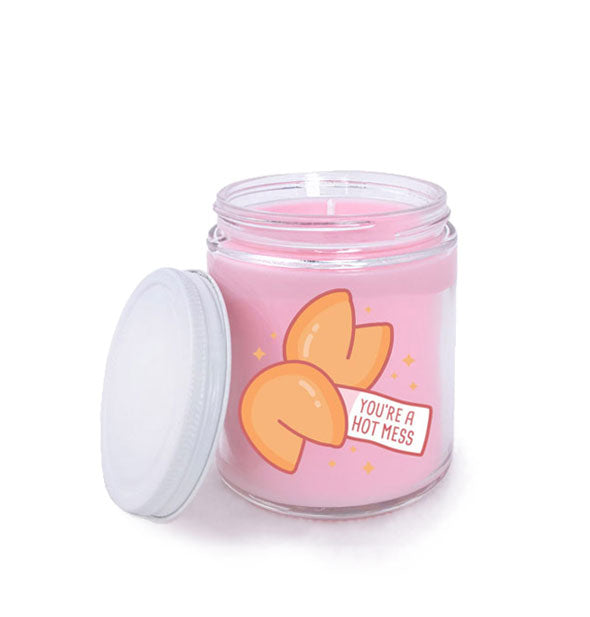 Jar candle with pink wax and white lid removed features illustration of two fortune cookies and the message, "You're a hot mess"