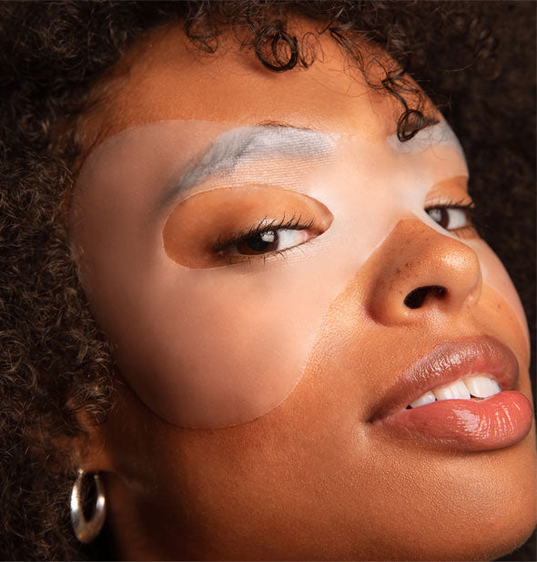 Model wears a partially see-through Lapcos Hydra Collagen Lifting Hydra-Gel Eye Mask over both eye, brow, and temple areas