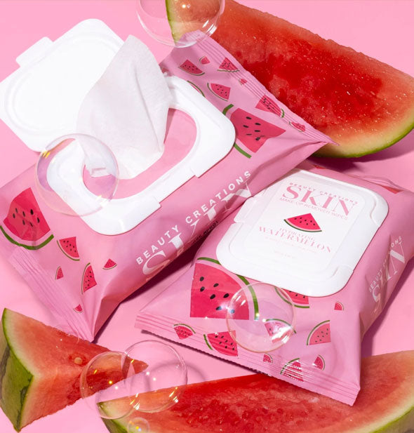One closed and one opened pack of Hydrating Watermelon Beauty Creations Skin Makeup Remover Wipes staged with pieces of watermelon and bubbles on a pink backdrop