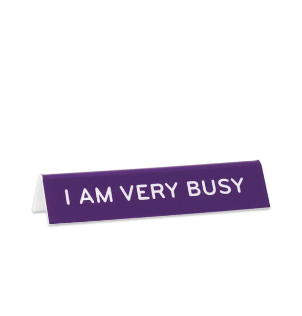 Rectangular purple desk sign says, "I am very busy" in white lettering