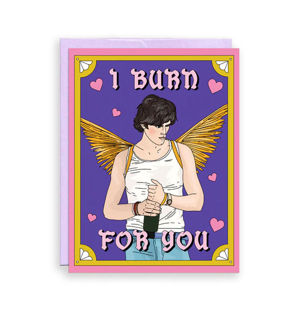 Purple greeting card with pink and gold border backed by a purple envelope features illustration of a winged Felix Catton from Saltburn surrounded by pink hearts and the message, "I burn for you" in pin lettering