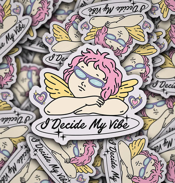 Pile of stickers with illustration of a winged cherub with shaggy pink hair and purple sunglasses atop the phrase, "I decide my vibe" in black script lettering accented by small stars