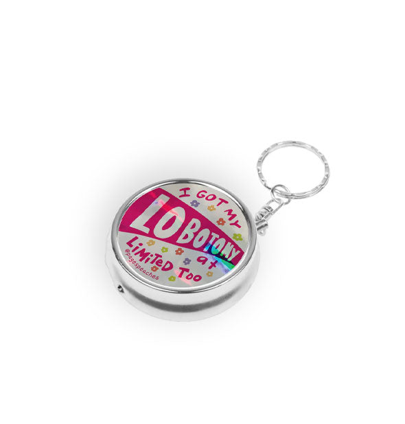 Silver pill case on keychain says, "I got my lobotomy at Limited Too" in red lettering accented with small colorful flower graphics