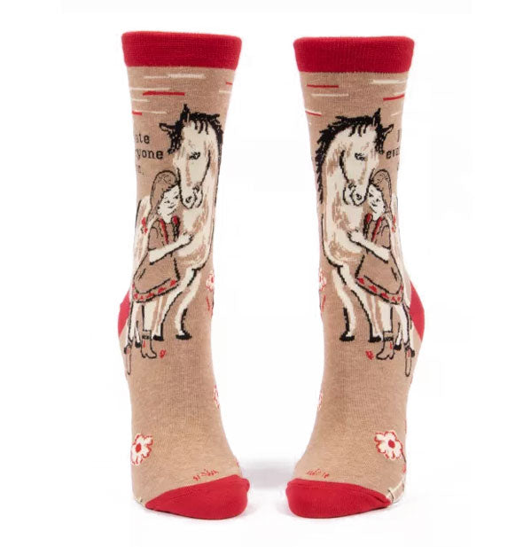 Pair of tan socks with red accents each feature a monochromatic design of a girl with horse in a pasture beneath the caption, "I hate everyone too" in black lettering