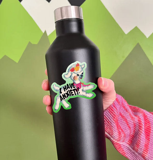 Model holds a black water bottle with an I Have Anxiety lamb sticker on it