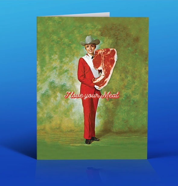 Green greeting card on a blue backdrop features image of a cowgirl in red suit holding a giant slab of raw meat and the caption, "I love your Meat" in shadowed script lettering