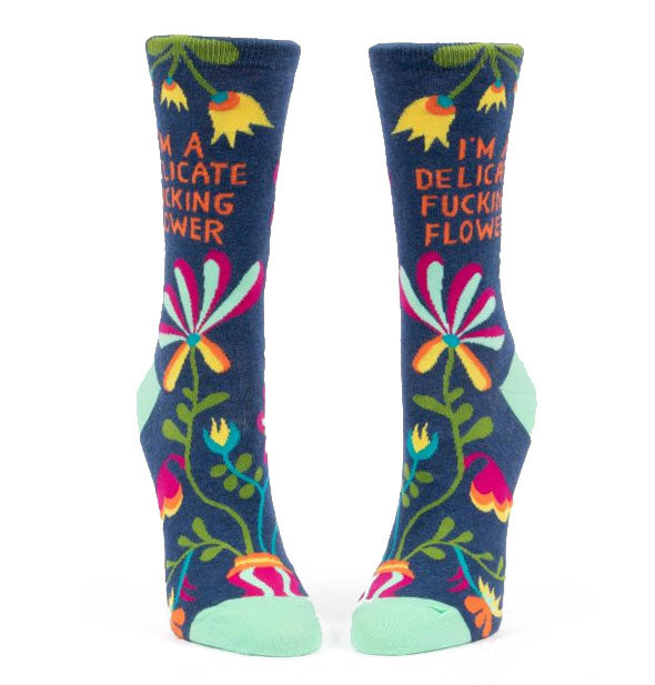Dark blue crew socks with teal accents and colorful florals say, "I'm a delicate fucking flower" on the ankles