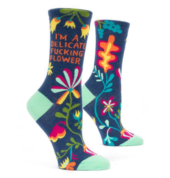 Dark blue crew socks with teal accents and colorful florals say, "I'm a delicate fucking flower" on the ankles