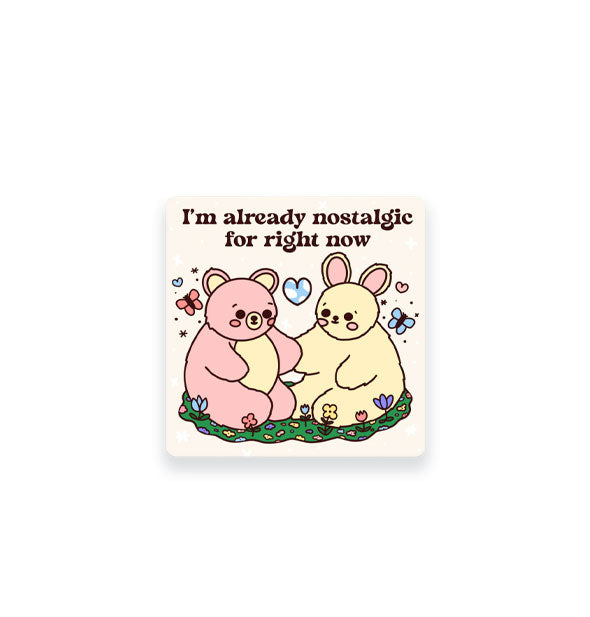 Square white sticker features illustration of a pink bear and yellow bunny surrounded by butterflies, flowers, and hearts under the caption, "I'm already nostalgic for right now" in black lettering