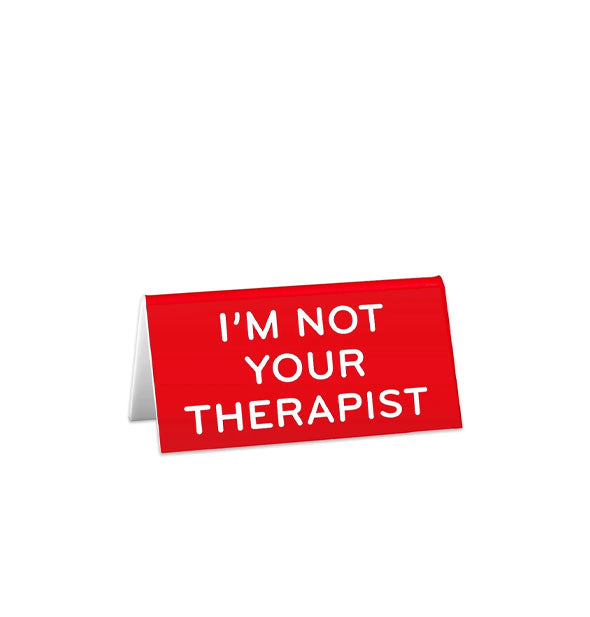 Rectangular red desk sign says, "I'm not your therapist" in white lettering