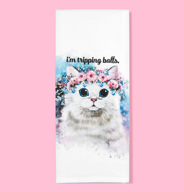 White dish towel on pink background features image of a wide-eyed white cat wearing a pink flower crown under the words, "I'm tripping balls."