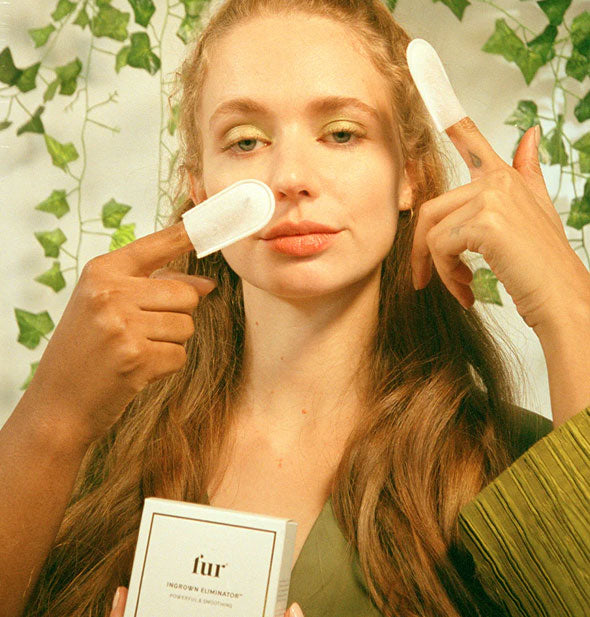 Models hold index fingers affixed with Fur Ingrown Eliminator Serum Infused Mitts up to another model's face