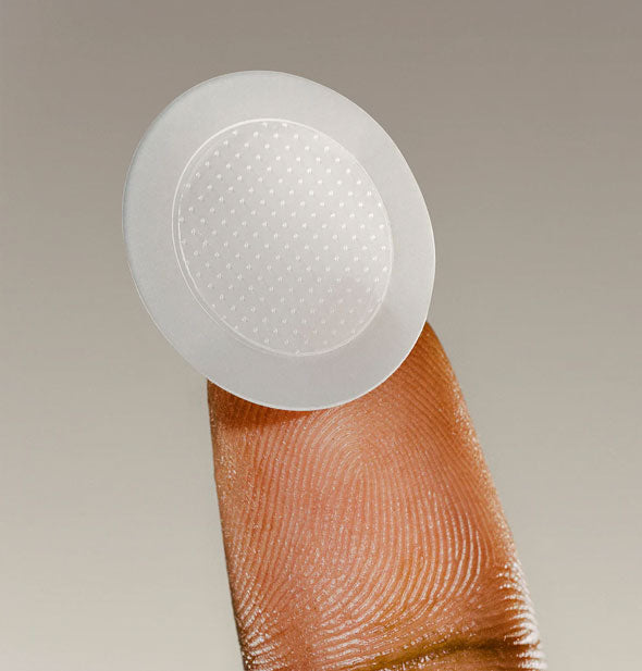 Extreme closeup of a fingertip holding a Ingrown Microdart Patch