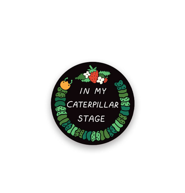 Round black sticker features illustration of a green caterpillar and strawberries flanked by white flowers with the caption, "In my caterpillar stage" in white lettering in the center