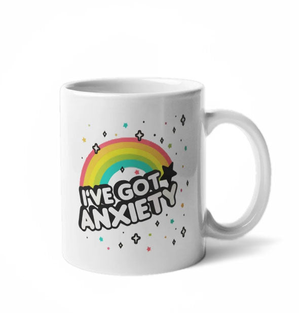 White coffee mug with rainbow and stars design says, "I've Got Anxiety"