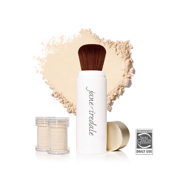 White Jane Iredale powder brush with gold cap removed and set to the side, two refill canisters nearby, and an enlarged product sample in the background in shade Ivory
