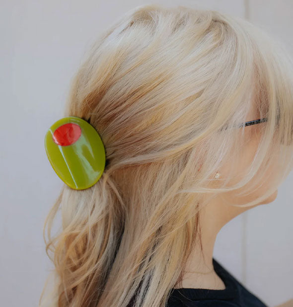 Model wears a green stuffed olive clip in a half-up hairstyle