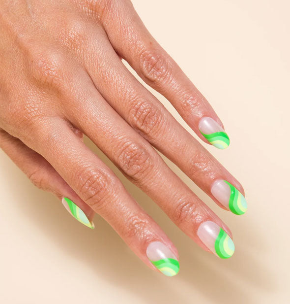 Model's hand wears a set of wavy green press-on nails