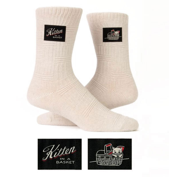 Pair of white socks, one of which features a black label that reads, "Kitten in a Basket," and the other with an image of a kitten in a basket