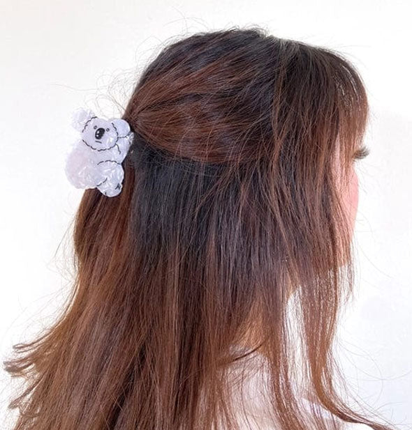 Model wears a gray koala bear claw clip in a partially swept-back hairstyle